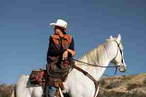 Photo gratuite silhouette de cow-boy à cheval contre une lumière chaude