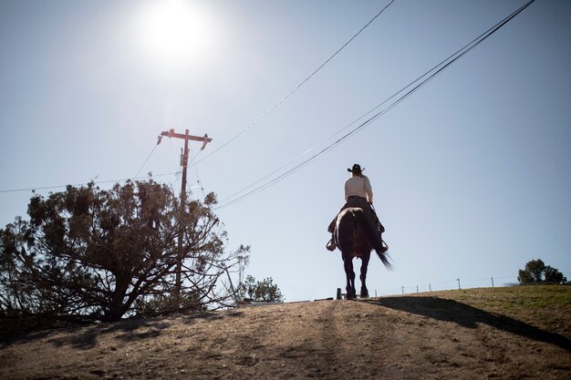 Silhouette de cow-boy à cheval contre une lumière chaude