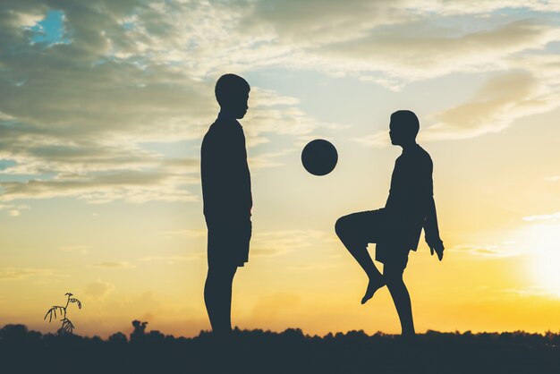 Silhouette d&#39;enfants jouant au football