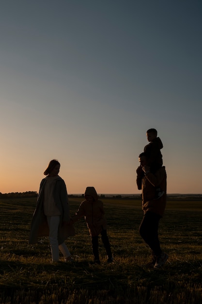 Photo gratuite silhouette familiale complète s'amusant au coucher du soleil