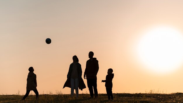 Silhouette familiale complète s'amusant au coucher du soleil