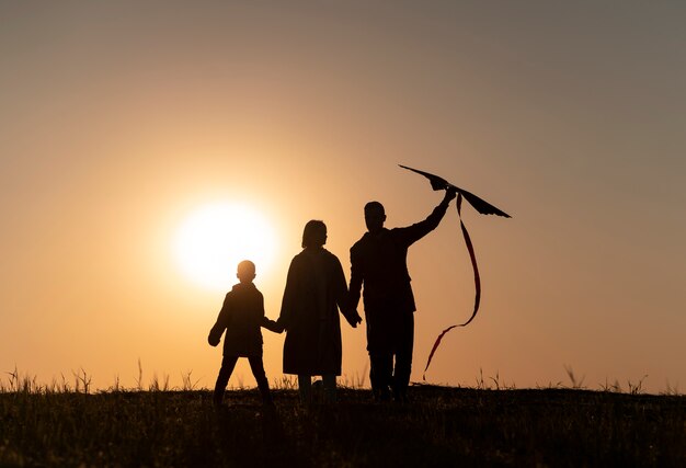Silhouette familiale complète s'amusant au coucher du soleil