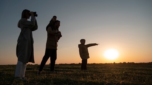 Silhouette familiale complète s'amusant au coucher du soleil