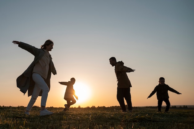 Photo gratuite silhouette familiale complète s'amusant au coucher du soleil