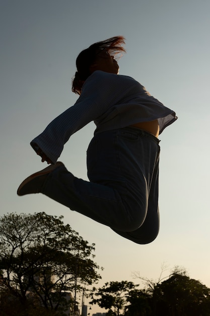 Silhouette de femme plein coup sautant au coucher du soleil