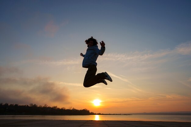 Silhouette d'homme plein coup sautant au coucher du soleil