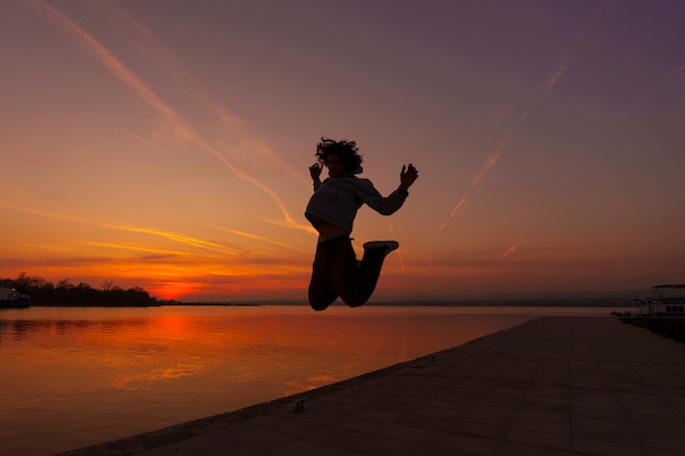 Silhouette d'homme plein coup sautant au coucher du soleil