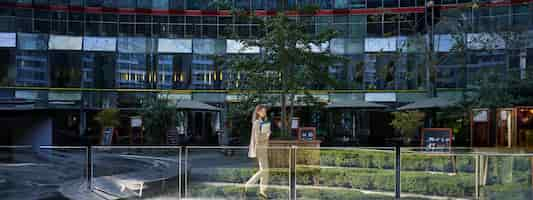 Photo gratuite silhouette d'une jeune femme d'affaires en costume beige marchant dans le centre-ville posant près des immeubles de bureaux