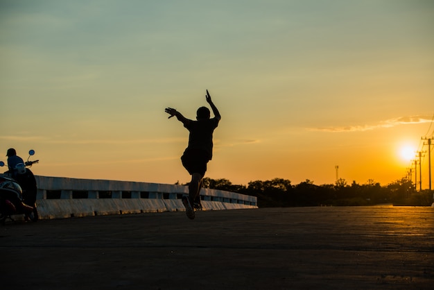 Silhouette d'un jeune homme de fitness en cours d'exécution sur le lever du soleil
