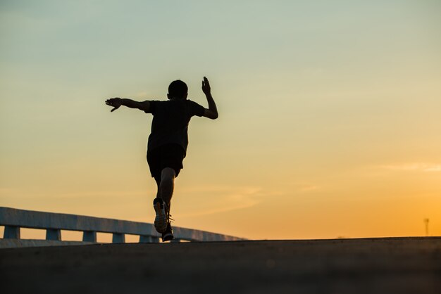 silhouette d'un jeune homme de fitness en cours d'exécution sur le lever du soleil