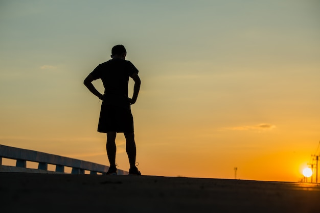 Photo gratuite silhouette d'un jeune homme de fitness en cours d'exécution sur le lever du soleil