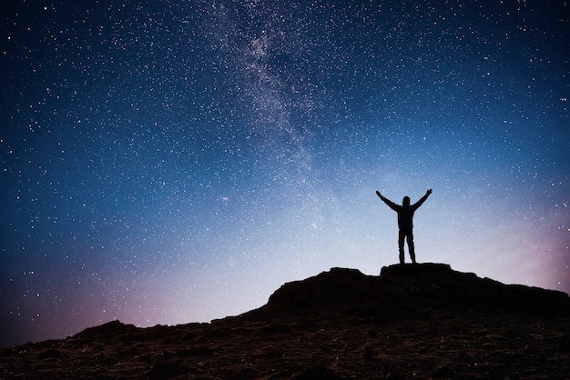 Silhouette jeune homme fond de la galaxie de la Voie lactée sur un ton de ciel étoilé brillant