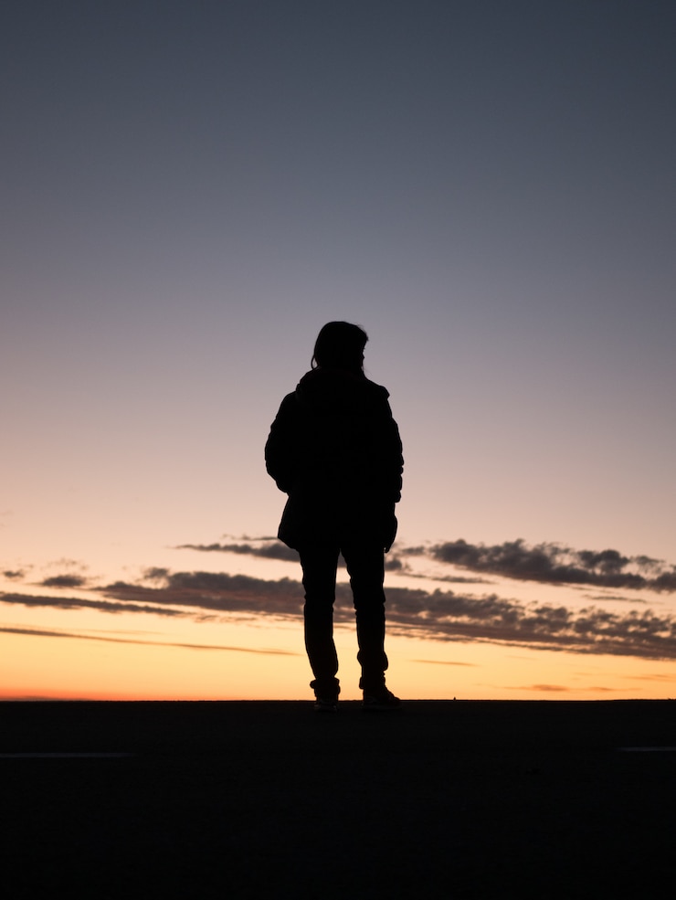 Photo gratuit silhouette d'une personne solitaire profitant de la belle vue sur le coucher du soleil