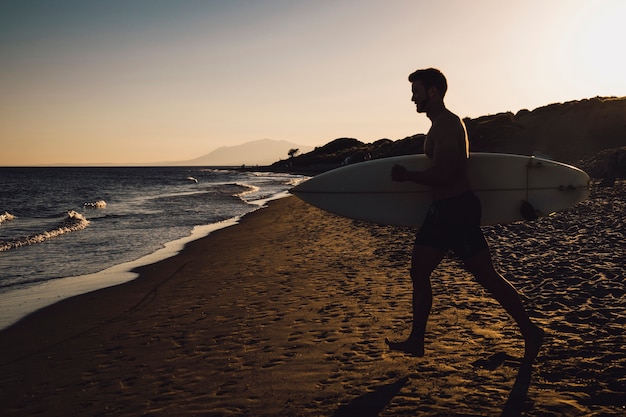 Silhouette de surfeur marchant vers la mer