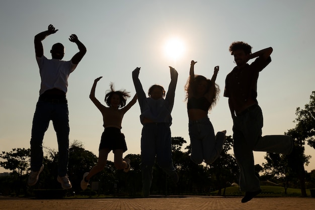 Photo gratuite silhouettes d'amis plein coup sautant au coucher du soleil