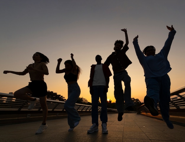 Silhouettes d'amis plein coup sautant au coucher du soleil