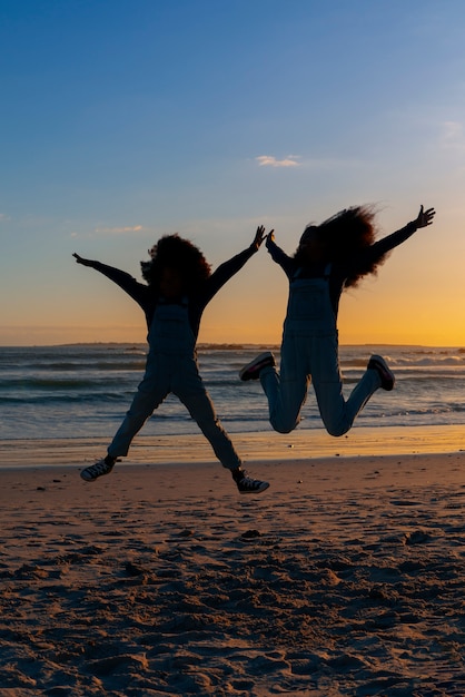 Silhouettes complètes de personnes sautant au coucher du soleil