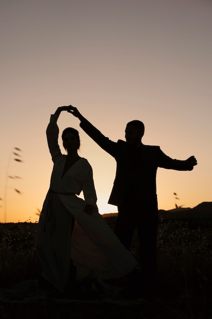 Silhouettes de couple plein coup dansant dans la nature