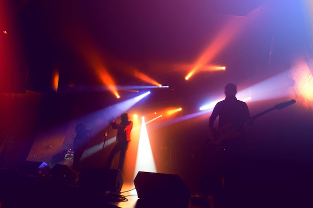 Silhouettes de groupe de rock sur scène au concert.