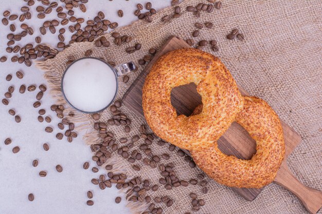 Simit roule sur une planche de bois avec un verre de boisson et des grains de café autour.