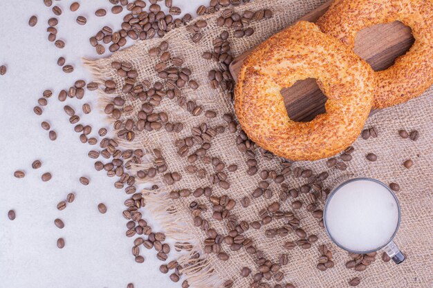 Simit roule sur une planche de bois avec un verre de boisson et des grains de café autour.