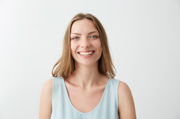 Sincère joyeuse heureuse jeune fille aux yeux bleus souriant en riant.