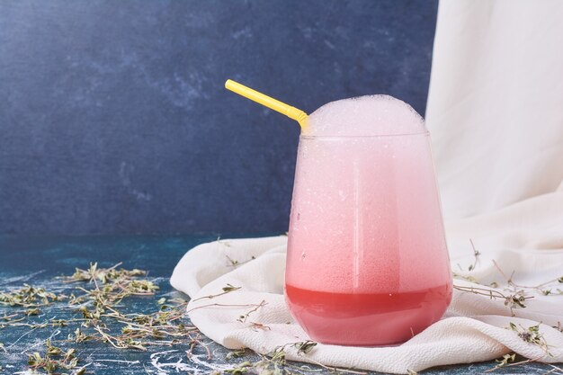 Sirop rose avec une tasse de boisson sur bleu.