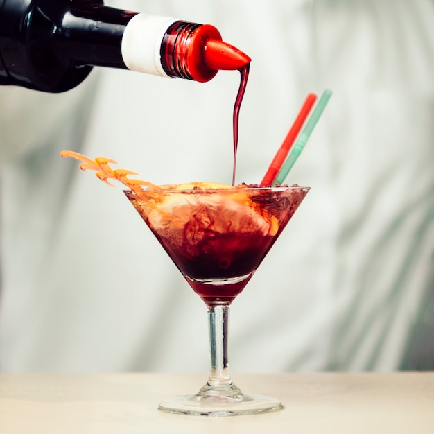 Sirop rouge versé dans un cocktail tropical