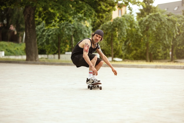 Skateur faisant un tour dans la rue de la ville en journée nuageuse. Jeune homme en baskets et casquette équitation et longboard sur l'asphalte. Concept d'activité de loisirs, sport, extrême, passe-temps et mouvement.