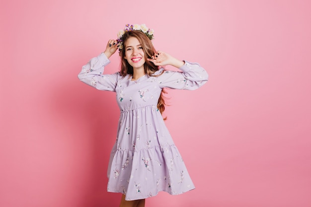 Slim femme adorable en robe violette s'amusant en studio