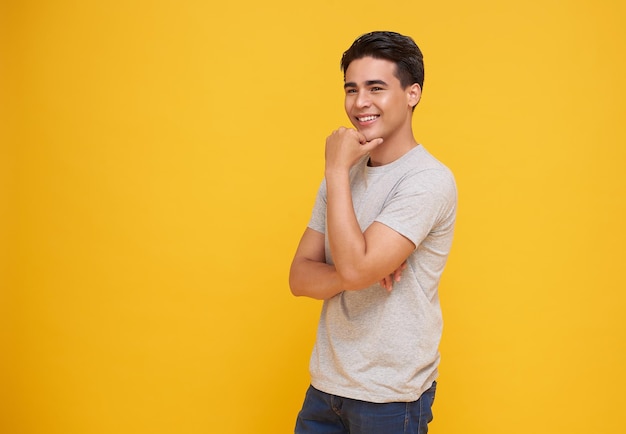 Photo gratuite smart beau sourire jeune homme asiatique pensant avec la main sur le menton isolé sur un fond jaune