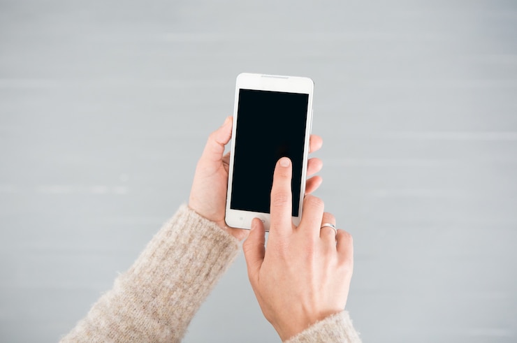 Photo gratuit smartphone blanc dans des mains féminines sur un fond gris