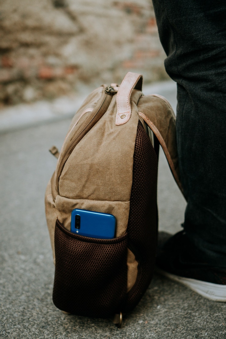 Photo gratuit smartphone bleu niché dans la poche latérale d'un sac photo fonctionnel marron