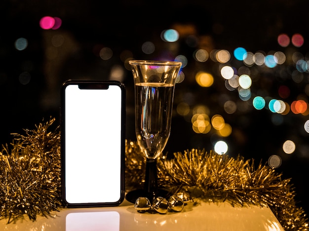 Photo gratuite smartphone près de verre de boisson et de tinsel