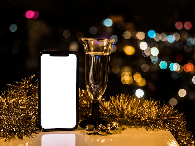 Smartphone près de verre de boisson et de tinsel