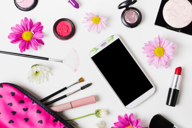 Smartphone et produits cosmétiques décoratifs sur table lumineuse