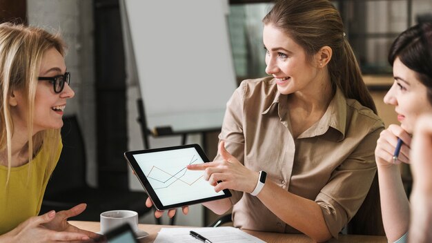 Smiley businesspeople using tablet lors d'une réunion à l'intérieur