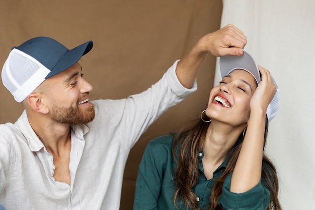 Photo gratuite smiley couple posant avec des chapeaux de camionneur coup moyen