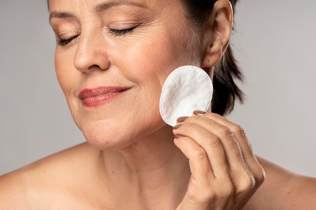 Smiley femme âgée à l'aide d'un coton pour le démaquillage