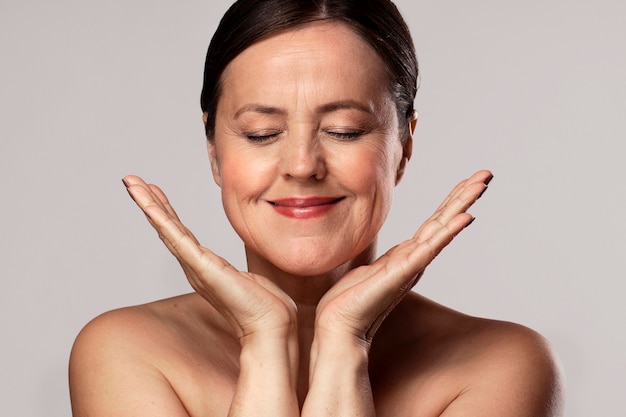 Smiley femme âgée avec du maquillage sur la préparation des soins de la peau