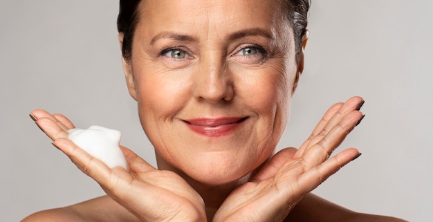 Smiley femme âgée avec un nettoyant moussant dans sa main