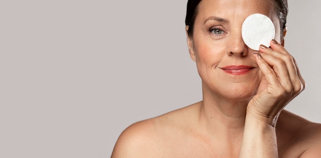 Smiley femme âgée posant avec un coton pour le démaquillage et l'espace de copie