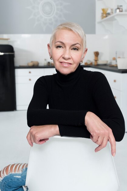 Smiley femme âgée souriante et posant dans la cuisine