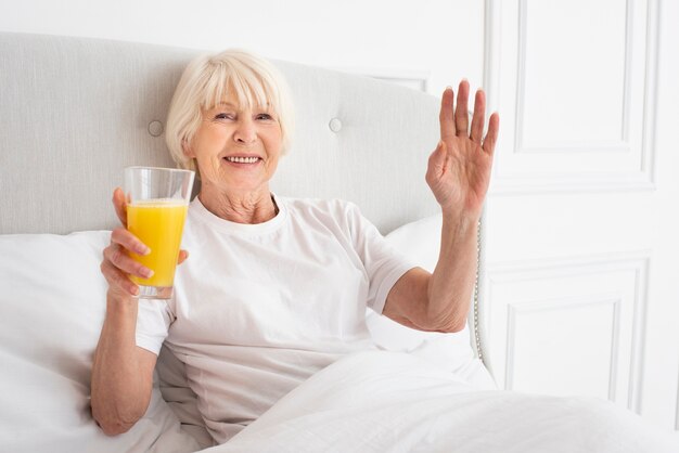 Smiley femme aînée tenant un verre avec du jus