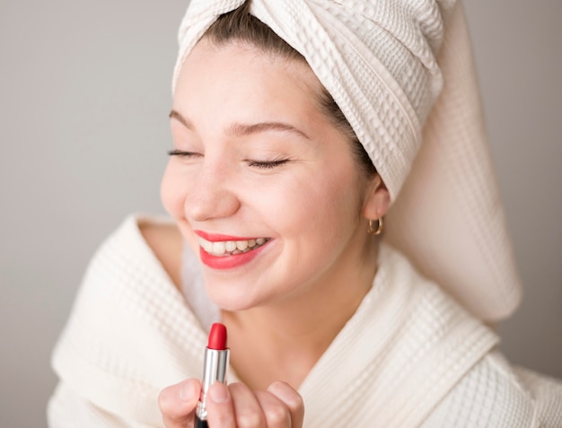 Smiley femme appliquant le rouge à lèvres