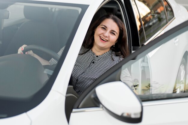 Smiley femme assise dans le siège du conducteur