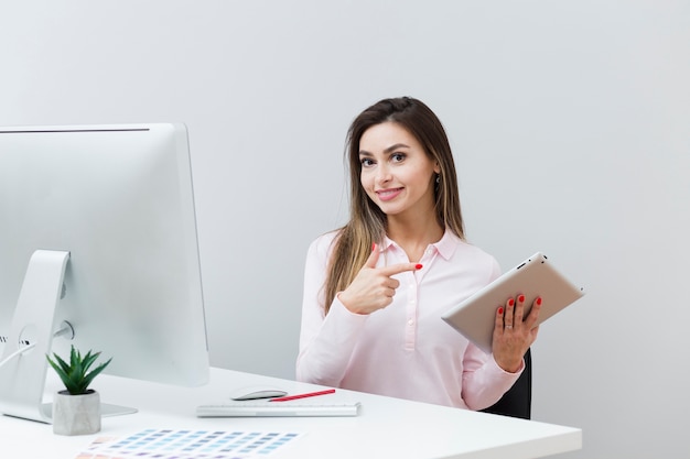 Smiley femme au bureau pointant sur tablette