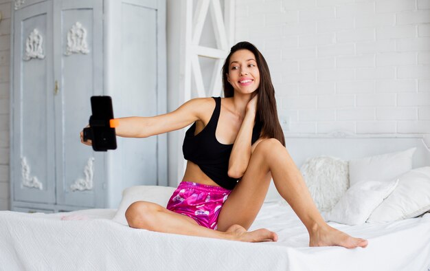 Smiley femme au lit prenant des selfies