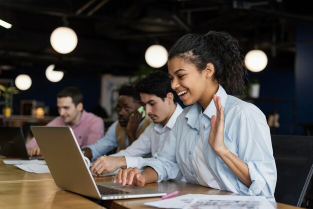 Smiley femme ayant un appel vidéo au bureau et agitant