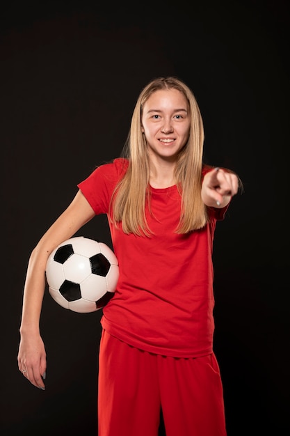 Smiley femme avec ballon de football pointant